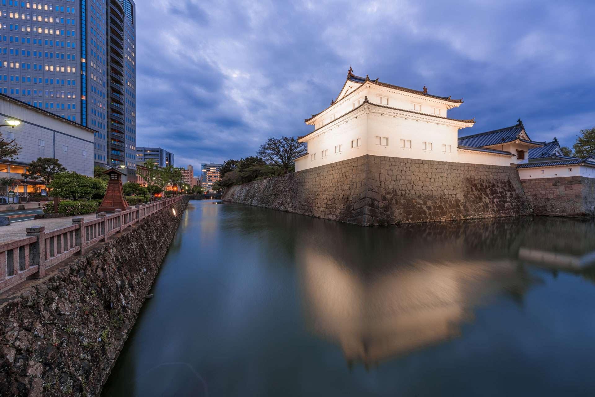 An illuminated castle and its moat at dusk.